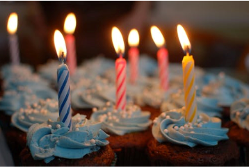 Cupcakes with blue icing and lit birthday candles