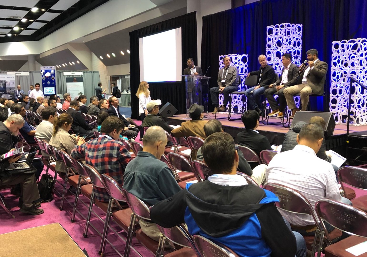 Woman asks questions of panel at IOT world with audience