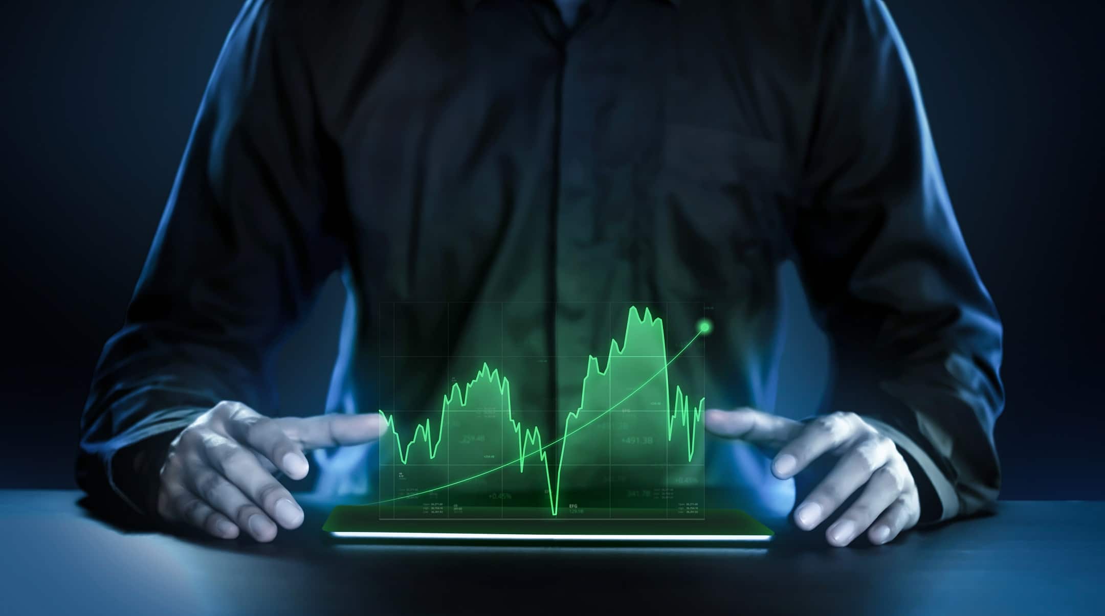 Business man showing profitable stock market graph hologram over a tablet.